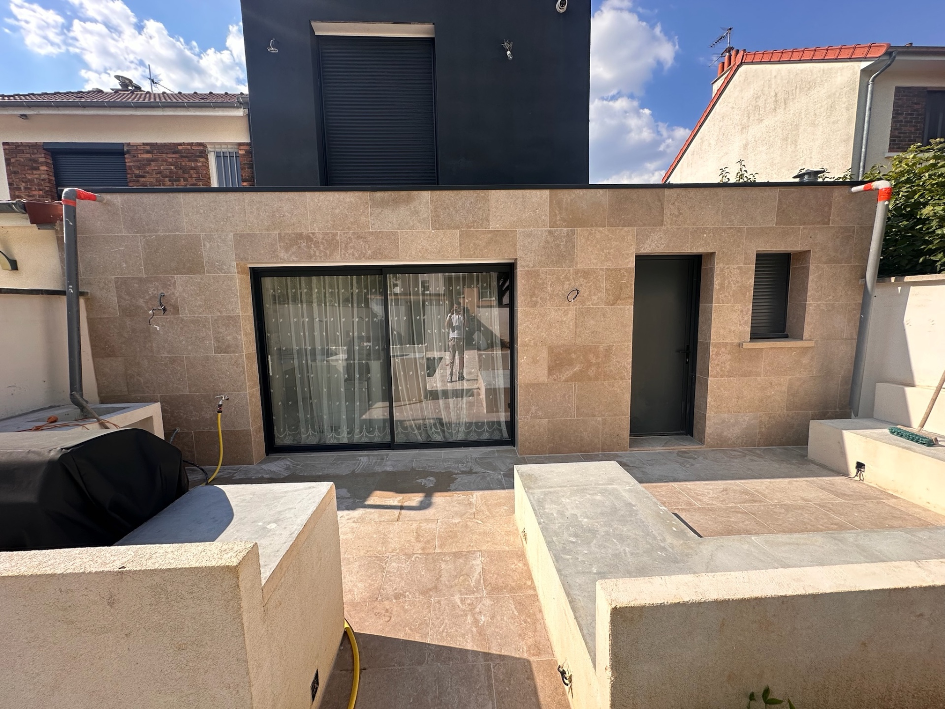 Façade et terrasse habillées en carrelage effet pierre avec menuiseries anthracite