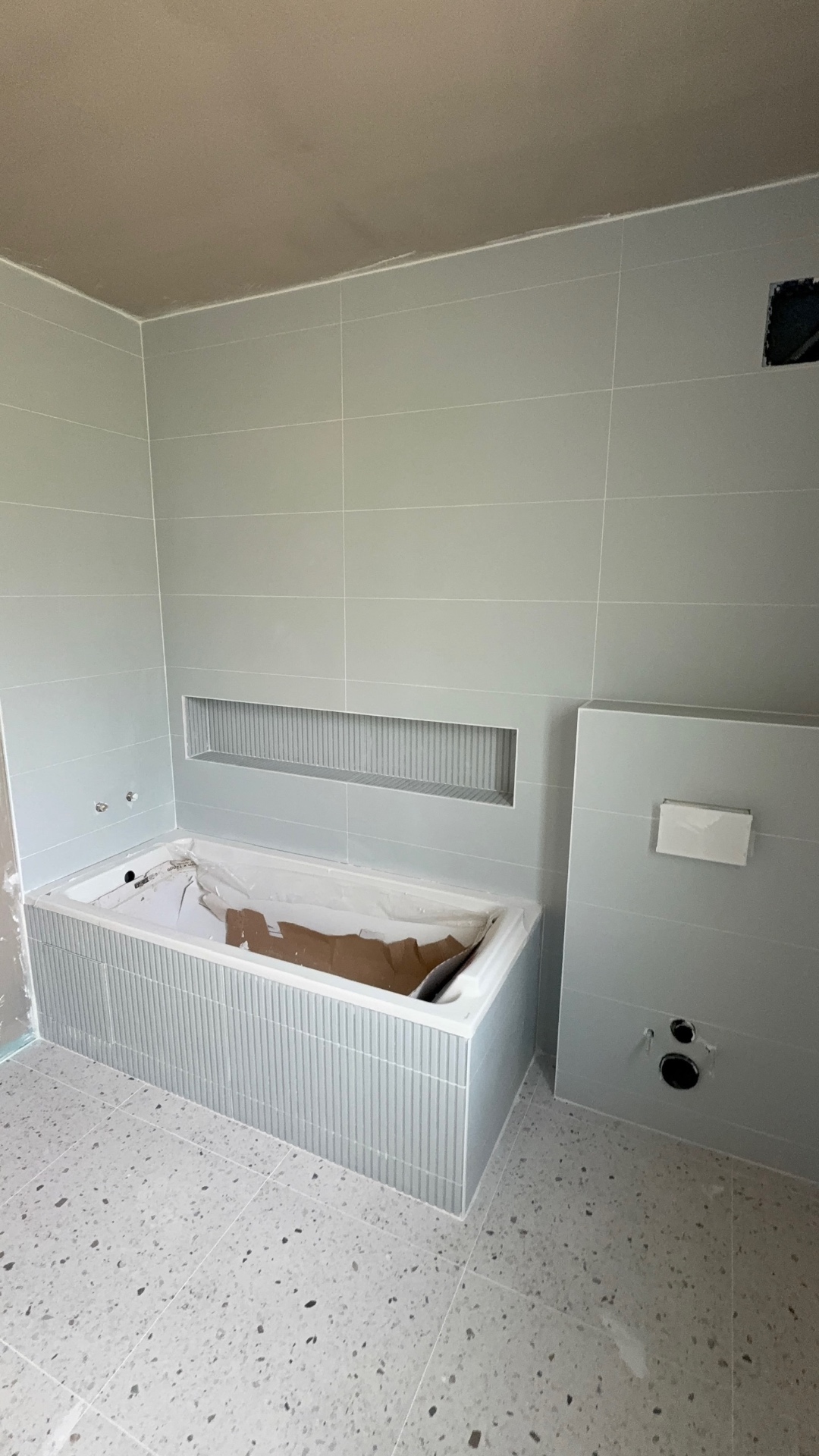 Salle de bain avec baignoire habillée de carrelage et niche murale carrelée