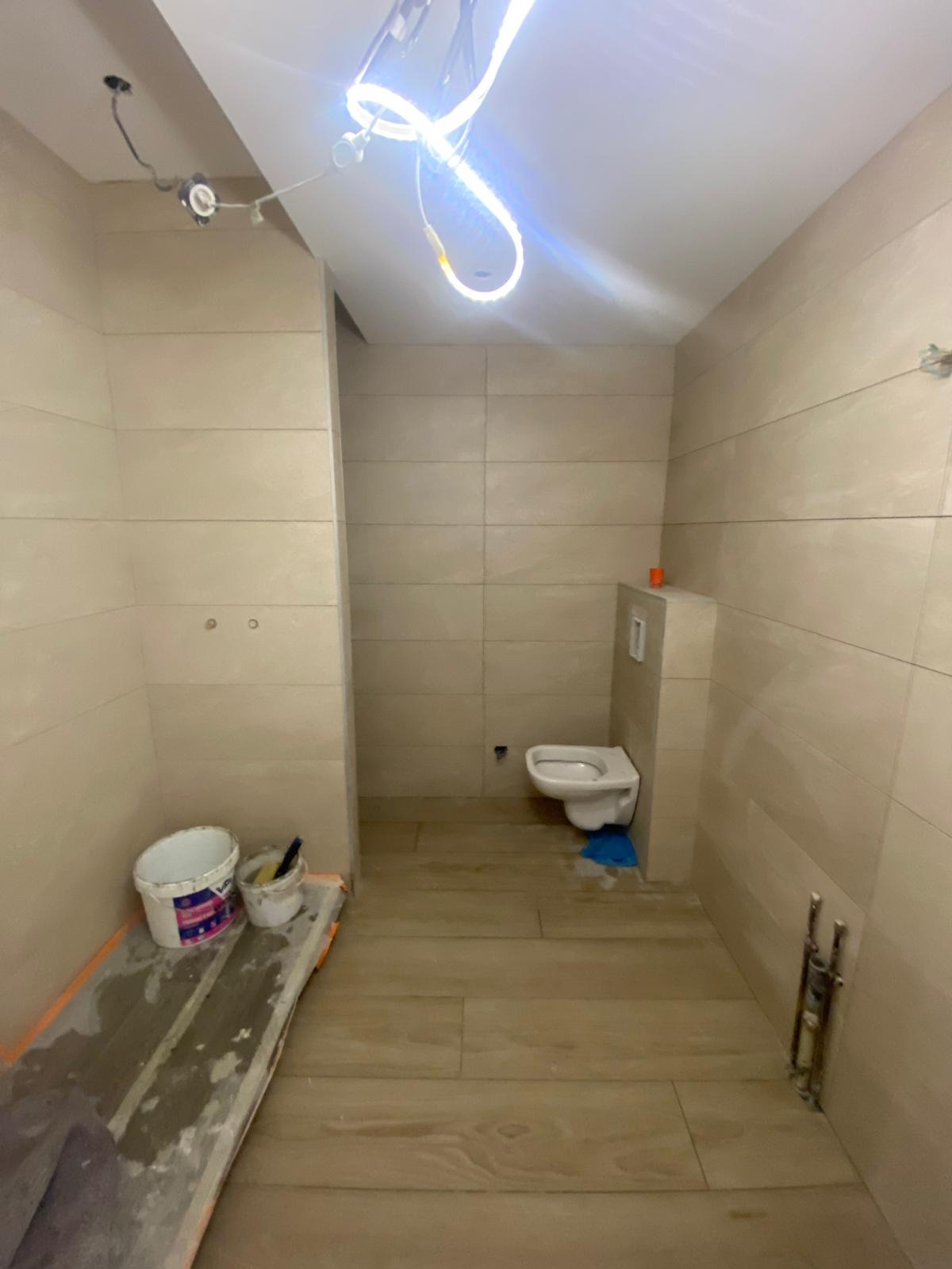 Salle de bain avec carrelage au sol et faïence murale beige et bois